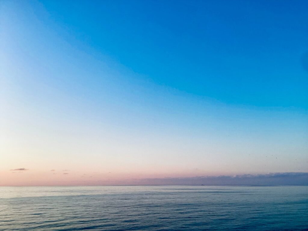 Serene view of the ocean at dawn with pastel sky colors creating a calming atmosphere.